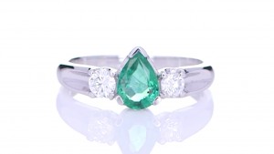 Green Emerald With Two Diamonds Placed On A Silver Ring