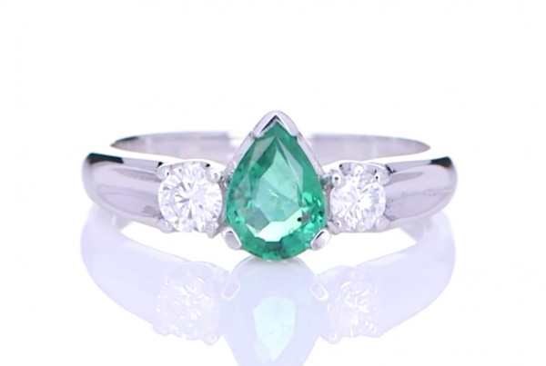Green Emerald With Two Diamonds Placed On A Silver Ring
