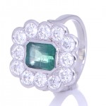 Twelve Diamonds Surrounding A Green Emerald Placed On A Silver Ring