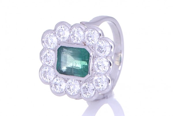 Twelve Diamonds Surrounding A Green Emerald Placed On A Silver Ring
