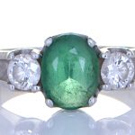 Green Emerald With Two Diamonds Mounted Onto A Platinum Ring