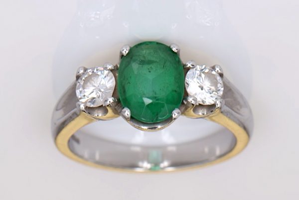 Green Emerald With Two Diamonds Mounted Onto A Platinum Ring