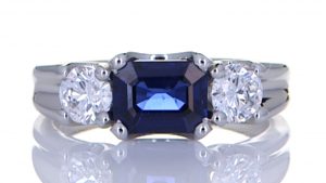 Two Diamonds With A Blue Sapphire Mounted Onto A Platinum Ring